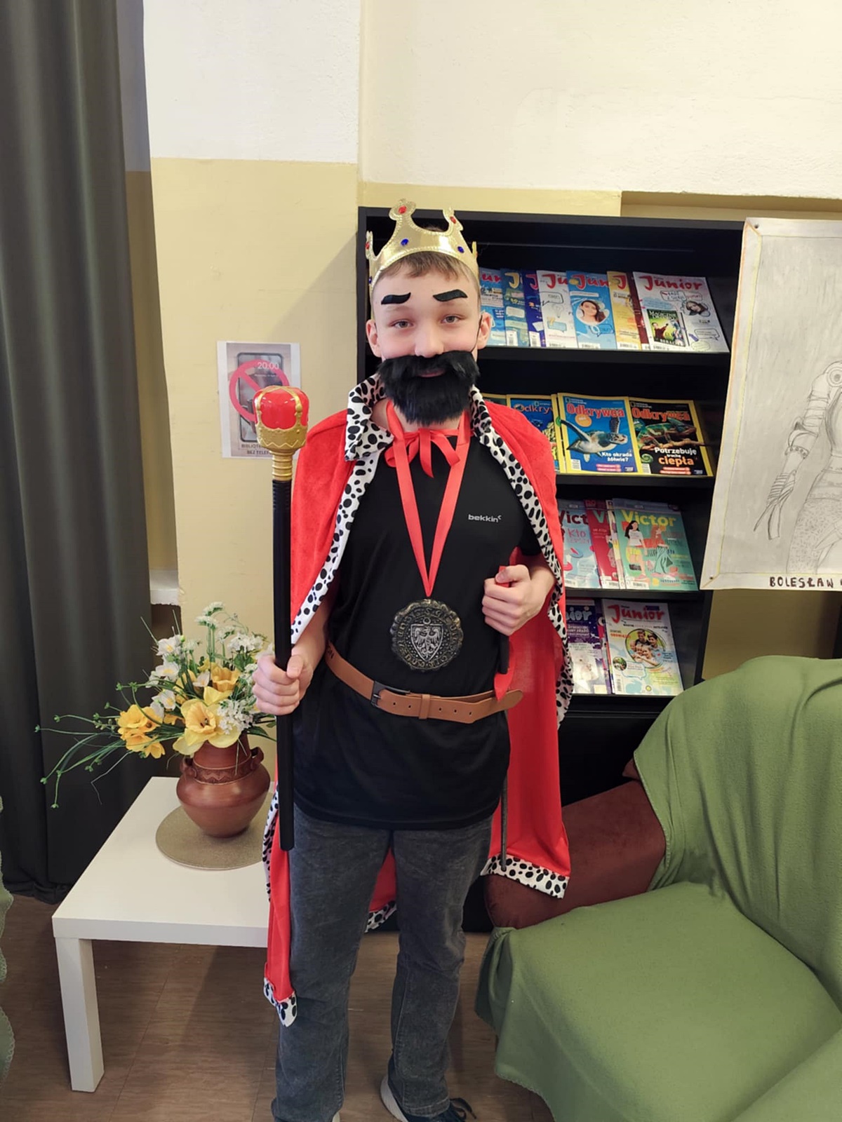 Uczeń przebrany za Bolesława Chrobrego. Czarny sweter, czerwona peleryna na piersi duży medal z orłem na czerwonej wstążce. Sztuczna czarna broda i wąsy. Złota korona. Przyklejone czarne brwi.