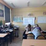 Dwa rzędy ławek. W ławkach uczennice przygotowujące materiały z okazji Światowego dnia wody/