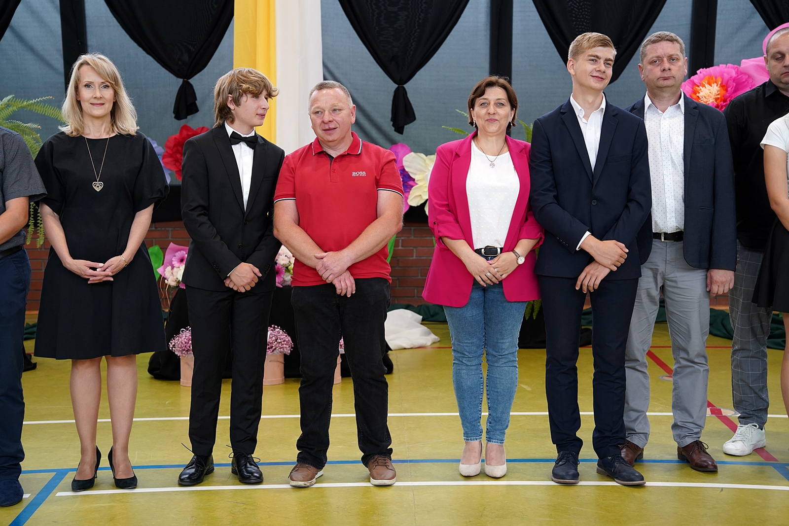 Grupa rodziców z dziećmi w oczekiwaniu na wręczenie gratulacji przez dyrekcję szkoły.
