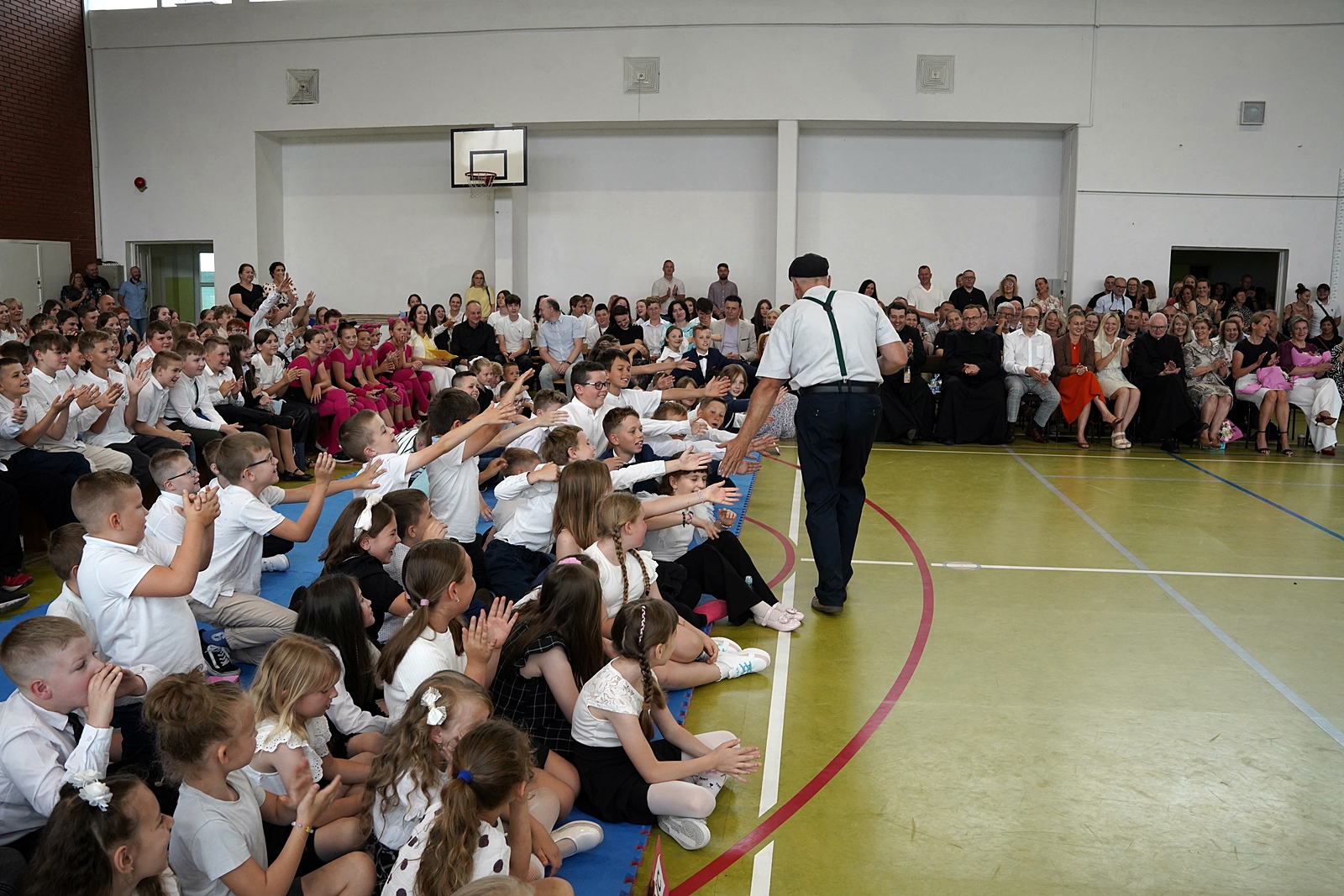 Grupa uczniów wyciąga dłonie do przebiegającego mężczyzny.