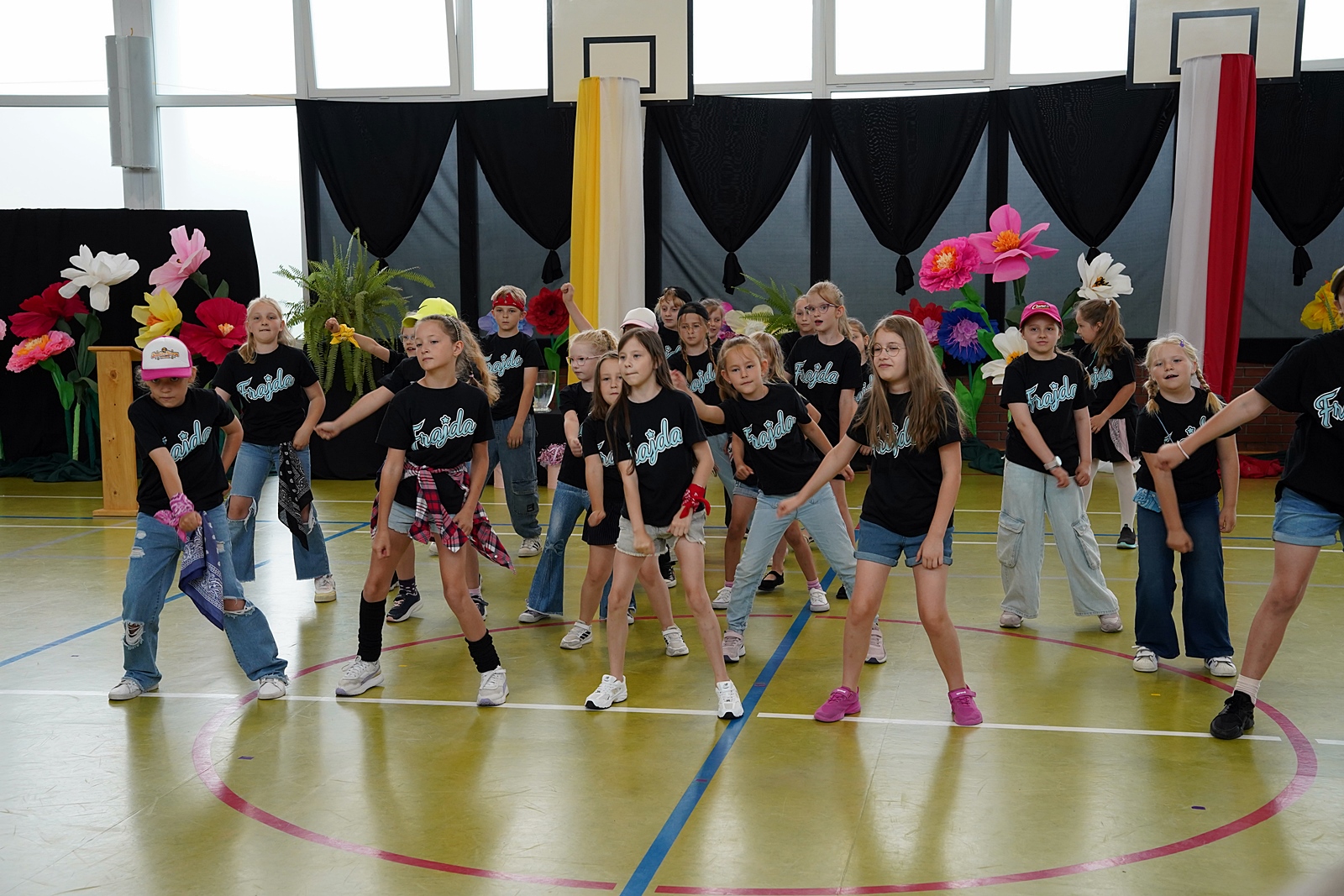 Grupa "Frajda" podczas występu. Szeroki rozkrok, ręce skierowane ku podłodze.