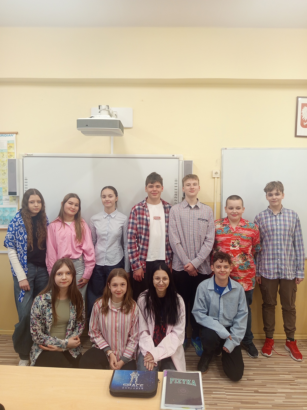 Grupa jedenastu uśmiechniętych uczniów pozujących w kolorowych koszulach.
