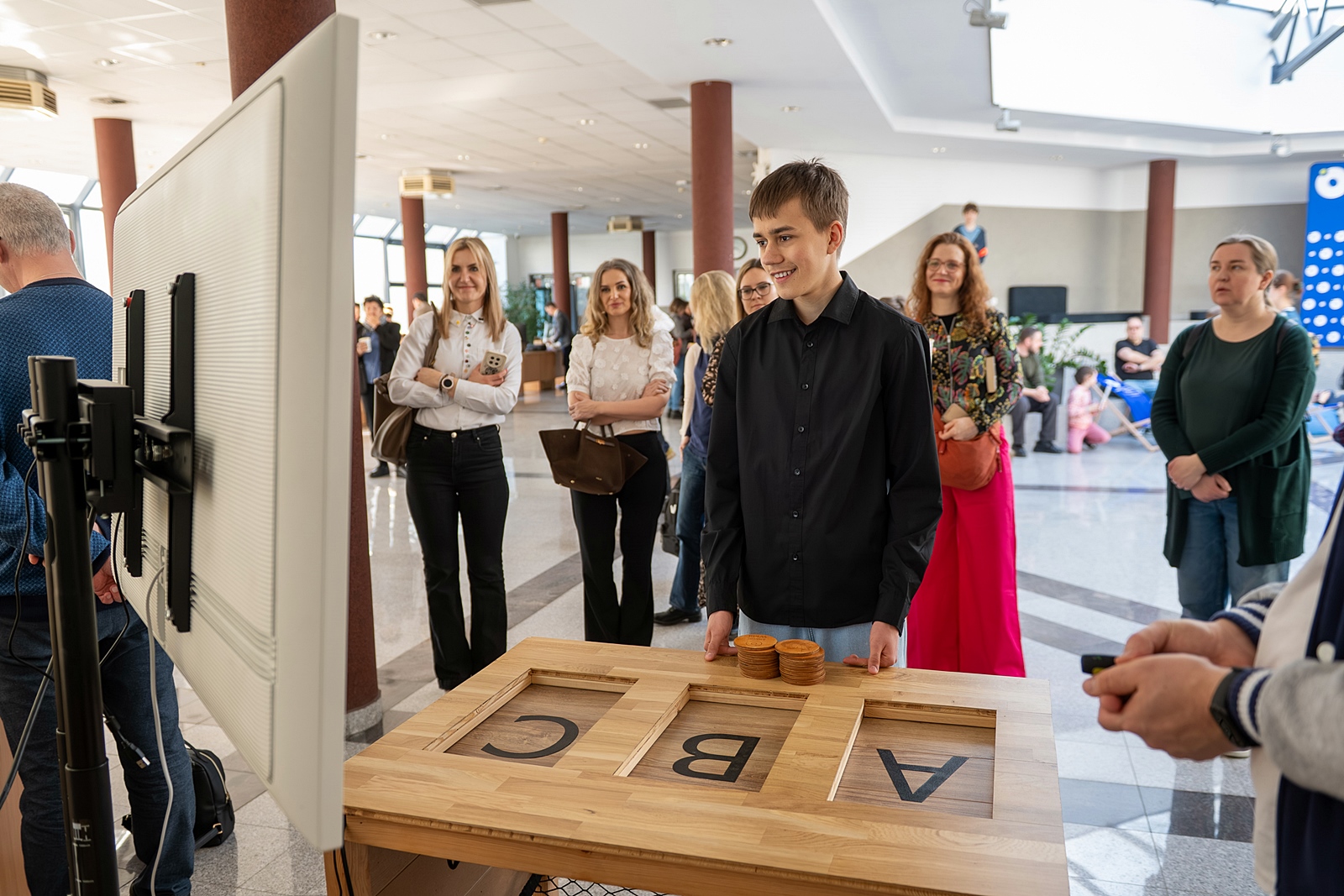 Uśmiechnięty uczeń przy stole konkursowym z literami: A, B, C