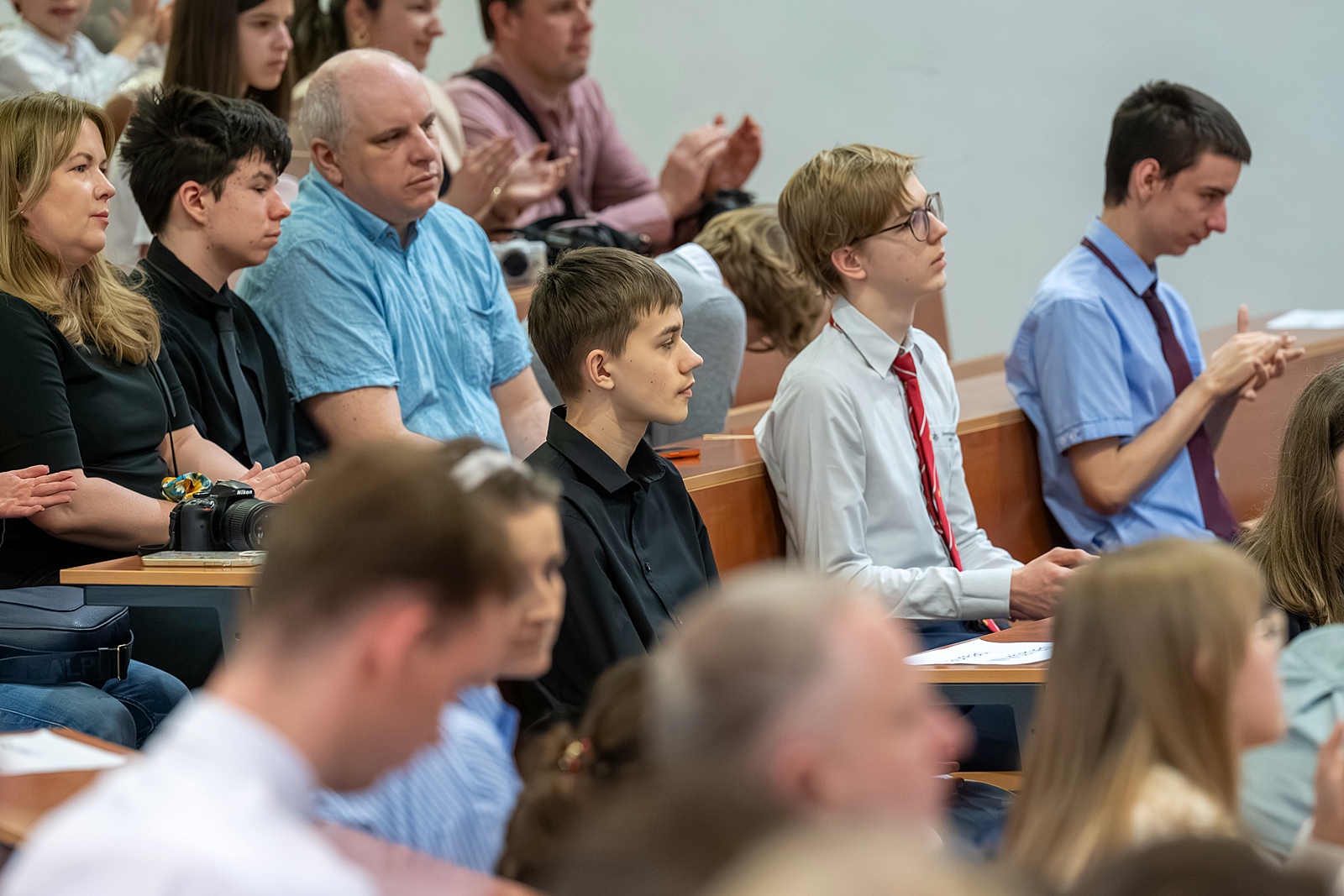 Zdjęcie sali wykładowej. Focus ustawiony na trzech uczestników.