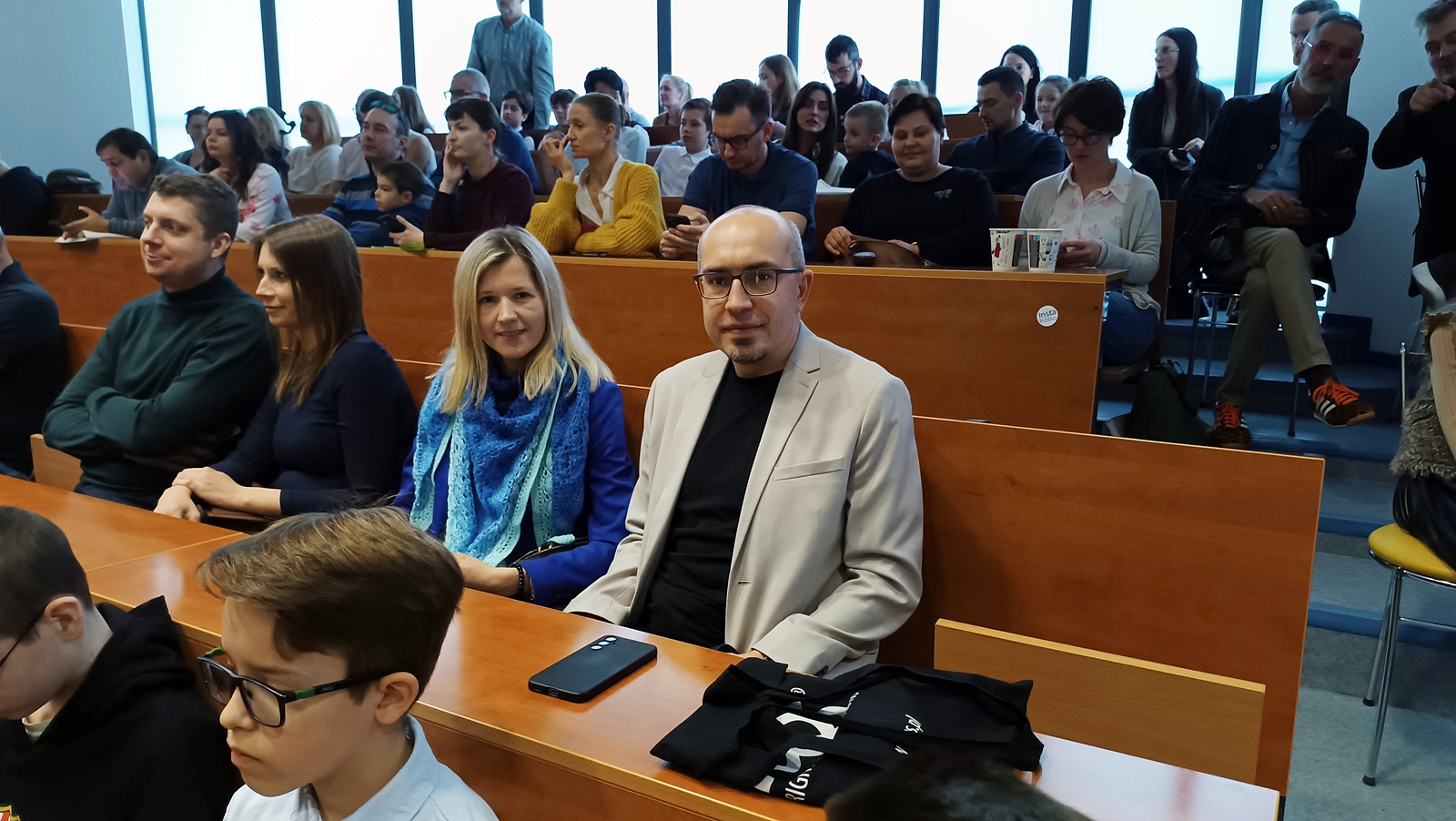 Sala wykładowa. Na pierwszym planie mężczyzna w jasnej marynarce i kobieta ubrana na niebiesko.